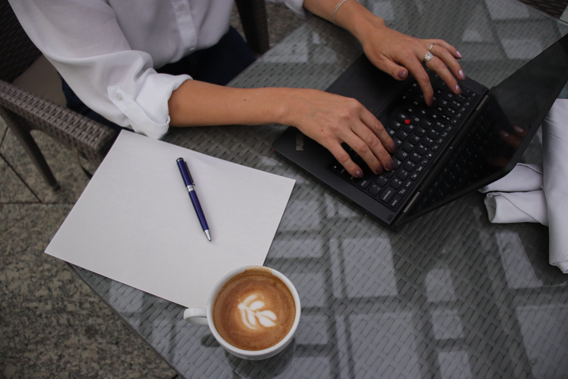 A laptop, notebook, and coffee on a table