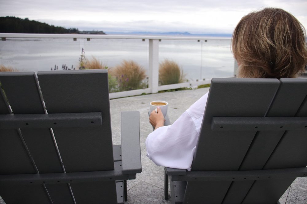 Ekaterina Thomas sitting with a cup of coffee, looking out over the water